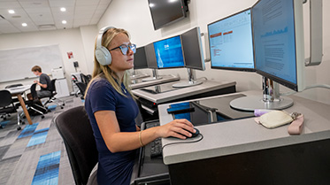 Student studying at a computer with headphoness on.